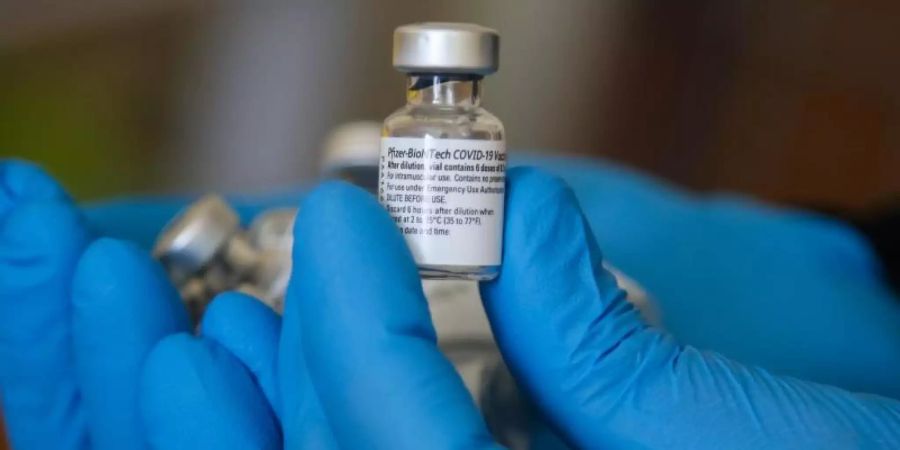 Ein Impfarzt hält einen Behälter mit dem Impfstoff gegen Covid-19 von Pfizer in einem Impfzentrum während der Impfung. (Archivbild). Foto: Dinendra Haria/SOPA Images via ZUMA Press Wire/dpa