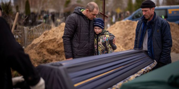 Wowa (10) wird von seinem Vater Ivan Drahun umarmt, während zwei Männer den Sarg seiner Mutter Maryna tragen. Sie starb in Butscha, als die Familie während der russischen Besetzung mehr als einen Monat lang in einem kalten Keller Schutz suchten. Emilio Morenatti/AP/dpa Beerdigung in Butscha