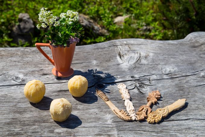 Der Trnič ist auf der Velika planina ein Symbol der Liebe. Wegen seiner, an die weibliche Brust angelehnten Form wird er auch «Busenkäse» genannt. Busenkäse Trnic Holztisch Blumen Messer Schnitzen