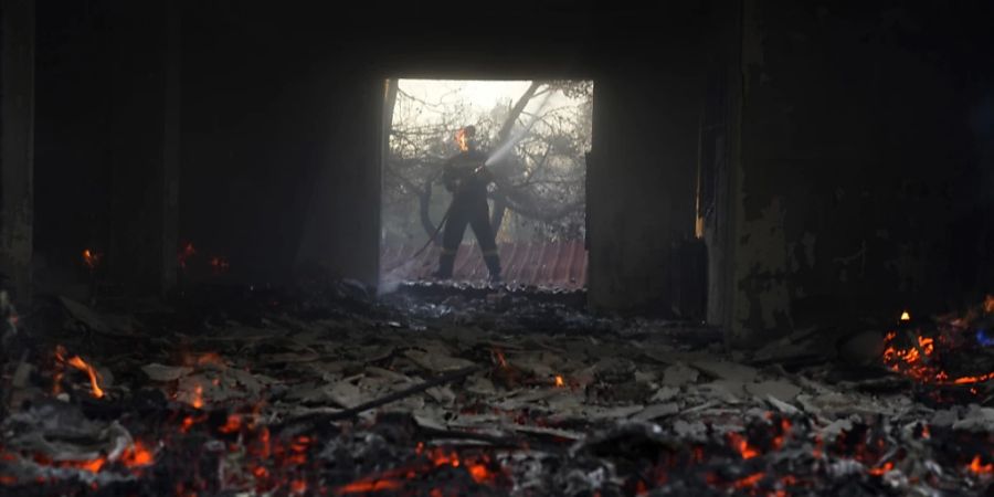 Ein Feuerwehrmann versucht, ein Feuer in einem Haus in der Nähe der Stadt Megara, westlich von Athen, zu löschen. Foto: Petros Giannakouris/AP/dpa