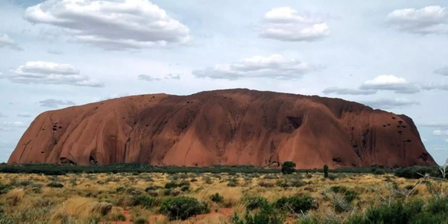 Eines der bekanntesten Wahrzeichen Australiens, der riesige Sandstein Uluru oder Ayers Rock ist in der zentralaustralischen Wüste zu sehen. Foto: picture alliance / dpa