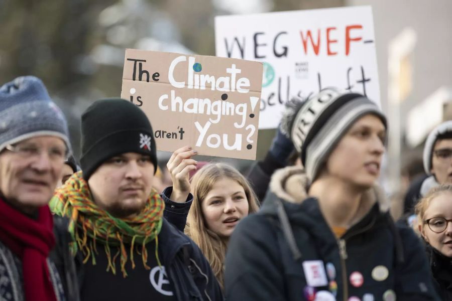 Demonstranten in Davos halten Plakate für den Klimaschutz hoch.