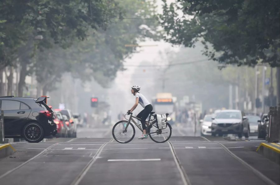 Eine Velofahrerin pedalt durch den Smog von Melbourne.