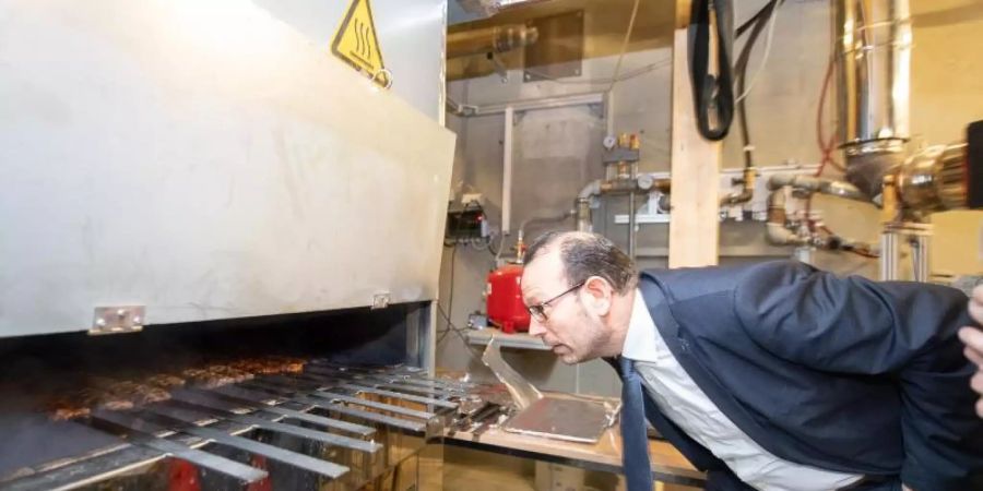 Mohammad Aleysa, Gruppenleitung Verbrennungs- und Umweltschutztechnik am Fraunhofer-Institut für Bauphysik IBP, schaut in einem Labor des IBP in einen Grill. Foto: Sebastian Gollnow/dpa