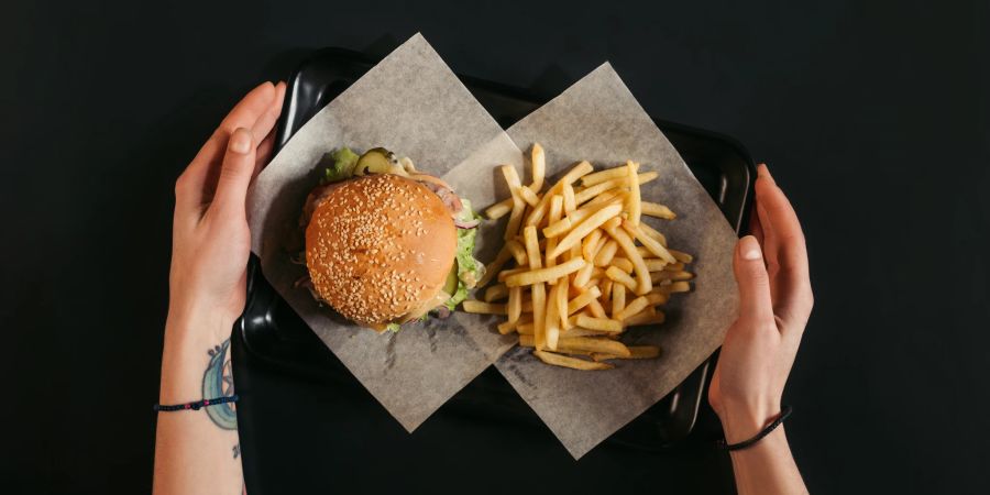 frauenhände halten fast food-tablett, schwarzer tisch