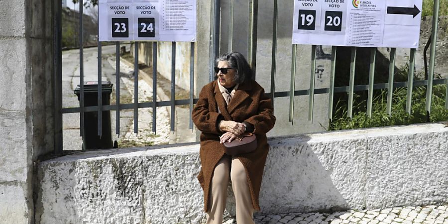 Eine Frau sitzt vor einem Wahllokal in Lissabon. In Portugal finden am Sonntag vorgezogene Parlamentswahlen statt, bei denen 10,8 Millionen registrierte Wähler 230 Abgeordnete für die Nationalversammlung, das Parlament des Landes, wählen. Foto: Joao Henriques/AP