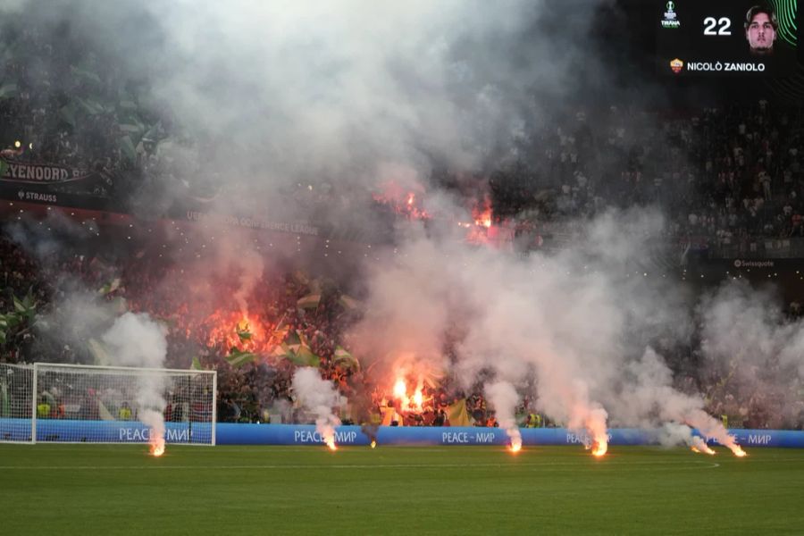 Aus dem Sektor von Feyenoord fliegen einige Pyros auf den Platz.