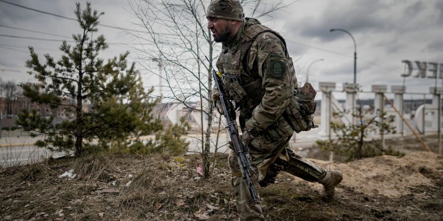 Ein ukrainischer Soldat geht am Stadtrand von Kiew in Schussposition.
