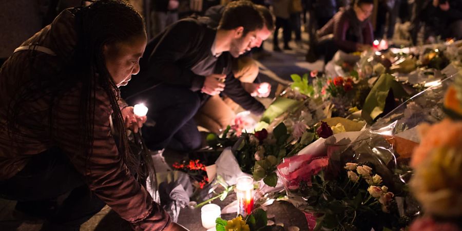 FILED - A woman lays a candle on Rue Alibert. In a coordinated series of attacks, extremists of the Islamic State (IS) killed 130 people. Photo: picture alliance / dpa