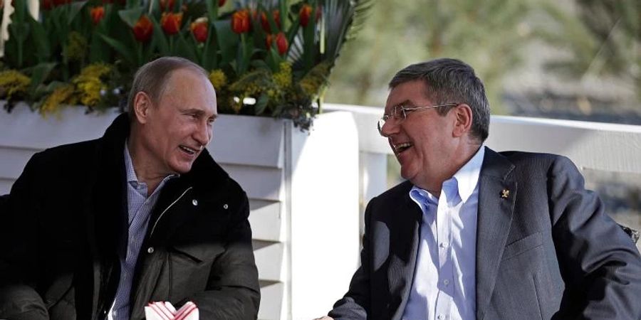 Der russische Präsident Wladimir Putin (l) und der IOC-Präsident Thomas Bach unterhalten sich in einem Cafe an der Promenade am schwarzen Meer während der Olympischen Spiele 2014 in Sotschi. Foto: David Goldman/AP/dpa