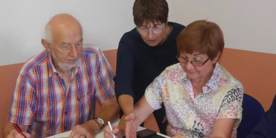 Digital-Botschafterin Birgitt Pfirrmann (M) zeigt im Seniorenbüro Landau Kniffe im Umgang mit einem Tablet. Foto: Karl Schupp/Senioren ins Internet Landau/dpa