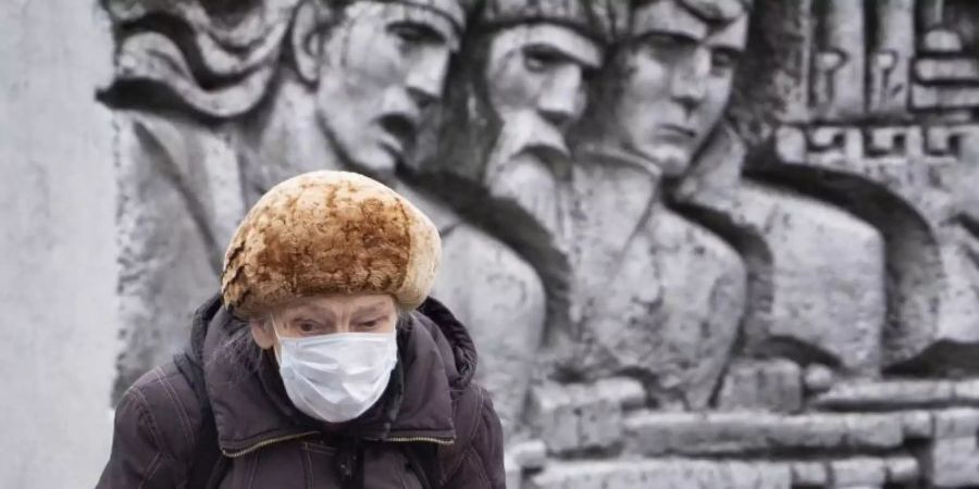 Eine ältere Frau in St. Petersburg vor einem Relief aus der Sowjetzeit. Foto: Dmitri Lovetsky/AP/dpa