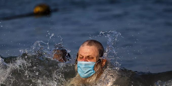 Ein Mann schwimmt mit Mundschutz an einem Strand in Tel Aviv. Foto: Oded Balilty/AP/dpa israel