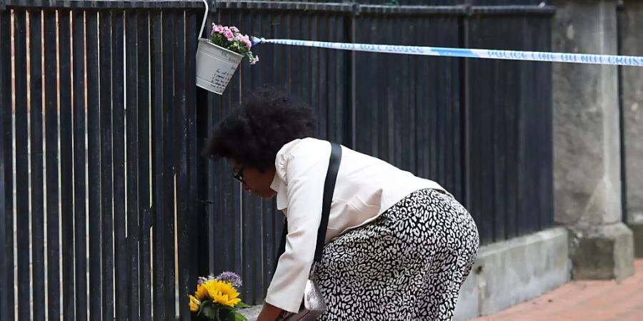 Eine Frau legt im Stadtzentrum von Reading Blumen nieder. Foto: Jonathan Brady/PA Wire/dpa