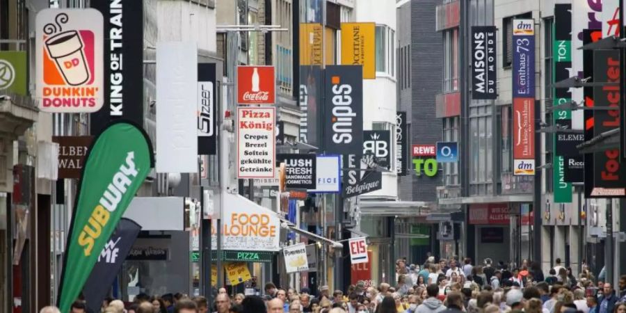 Passanten bummeln auf der Hohen Strasse, einer Fussgängerzone in der Kölner Innenstadt. Foto: Henning Kaiser/dpa