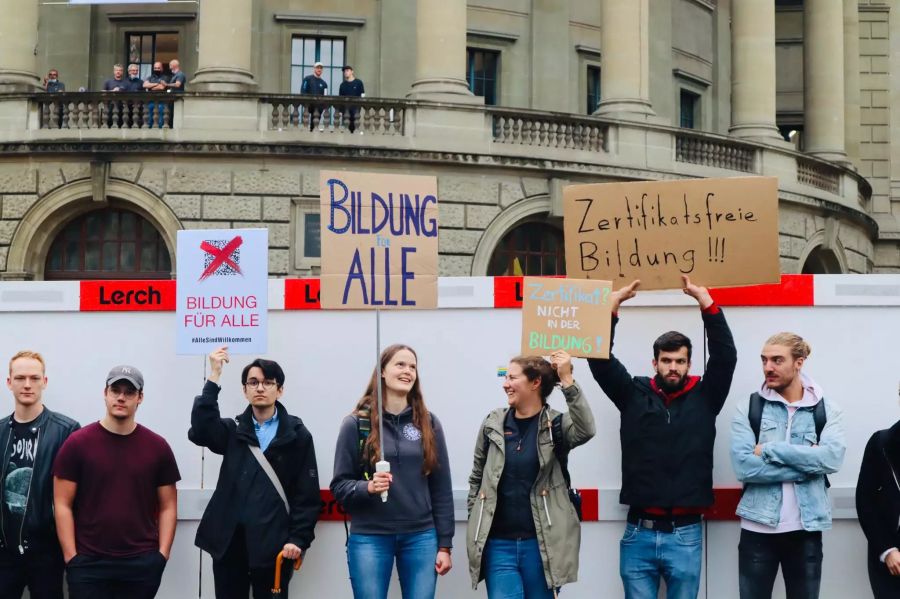 Mehrere Demonstranten halten Schilder und Plakate hoch.