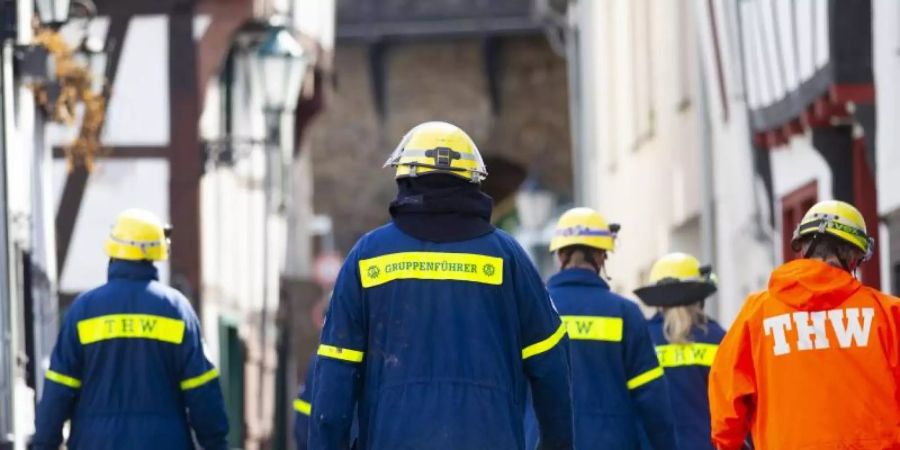 Mitglieder des Technischen Hilfswerks (THW) gehen bei Räumarbeiten nach der Unwetter-Katastrophe in Nordrhein-Westfalen durch einen zerstörten Ort. Foto: Thomas Banneyer/dpa