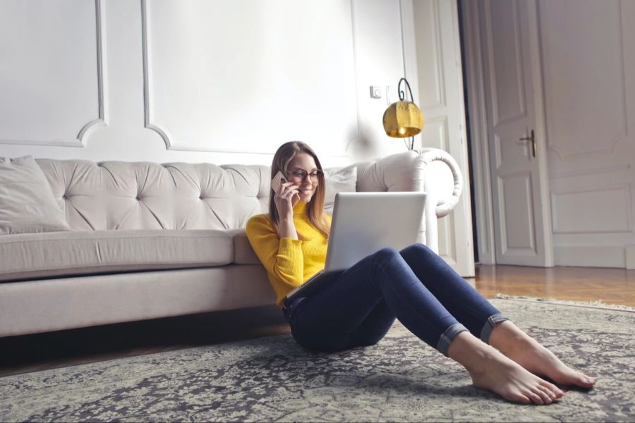 Frau Laptop barfuss Teppich Sofa Wohnzimmer Flexibilität Smartphone