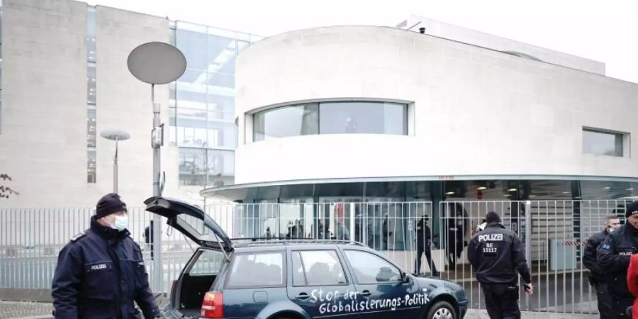 Ein Auto steht vor dem Tor des Bundeskanzleramts. Auf der Tür ist die Aufschrift «Stop der Globalisierungs-Politik» zu lesen. Foto: Michael Kappeler/dpa