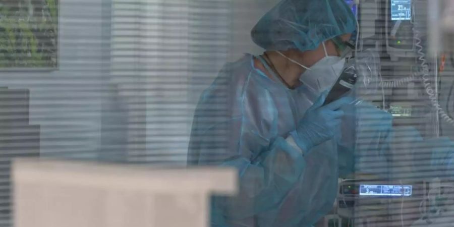 Eine Pflegerin versorgt in der Intensivstation eines Krankenhauses einen Coronapatienten. Foto: Henning Kaiser/dpa