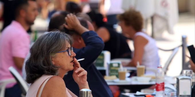 Eine Frau raucht im Aussenbereich einer Bar in Malaga. Das Nachtleben werde in Spanien landesweit unterbunden, das Rauchen im öffentlichen Raum verboten, wenn der Sicherheitsabstand nicht eingehalten werden kann, und Alkohol dürfe nicht mehr im Freien getrunken werden. Coronavirus - Spanien
