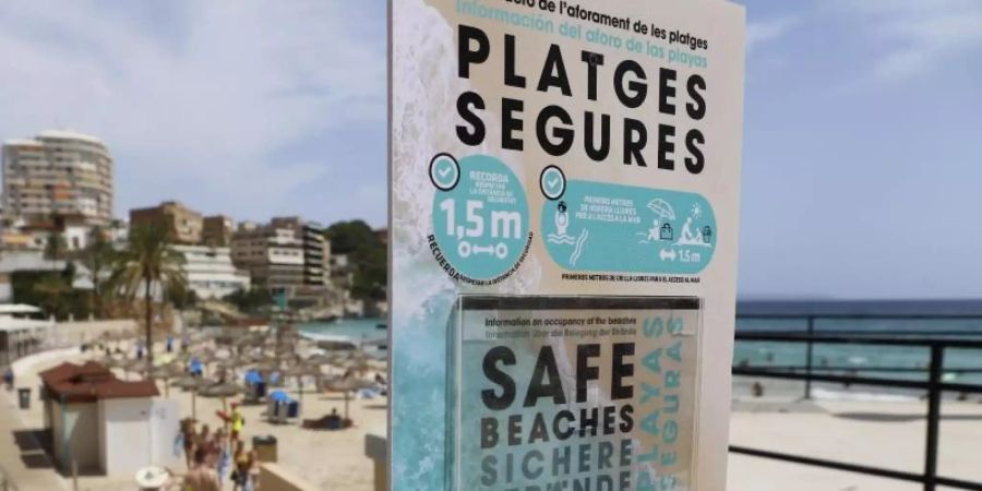 Ein Schild am Eingang zum Strand von Cala Major weist auf die Sicherheitsmassnahmen hin, die die Verbreitung des Coronavirus verhindern sollen. Foto: Clara Margais/dpa