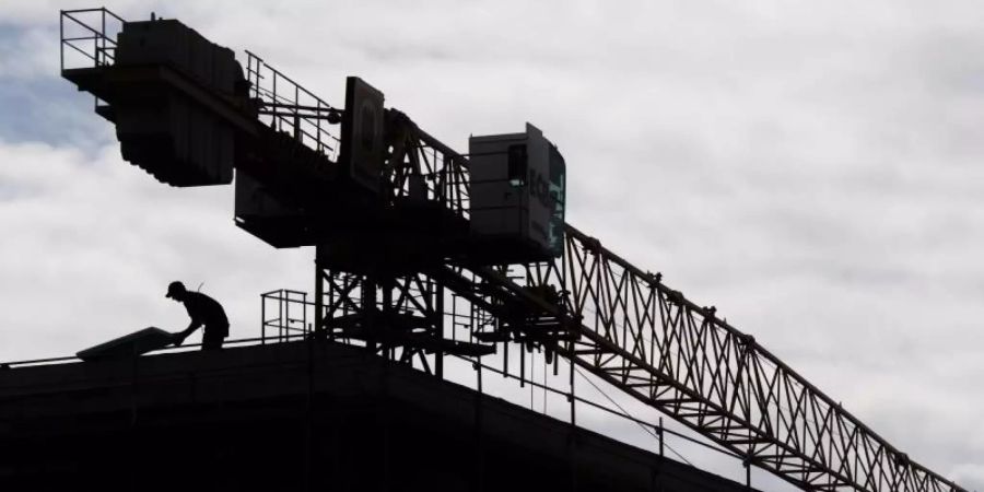 Ein Arbeiter arbeitet auf dem Dach eines Rohbaus in einem neuen Wohnquartier in Hannover. Foto: Julian Stratenschulte/dpa