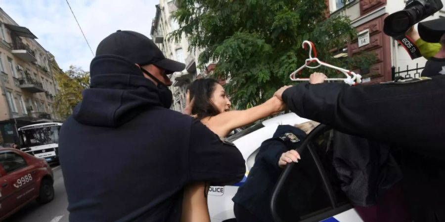 Polizisten nehmen die nackte Aktivistin fest