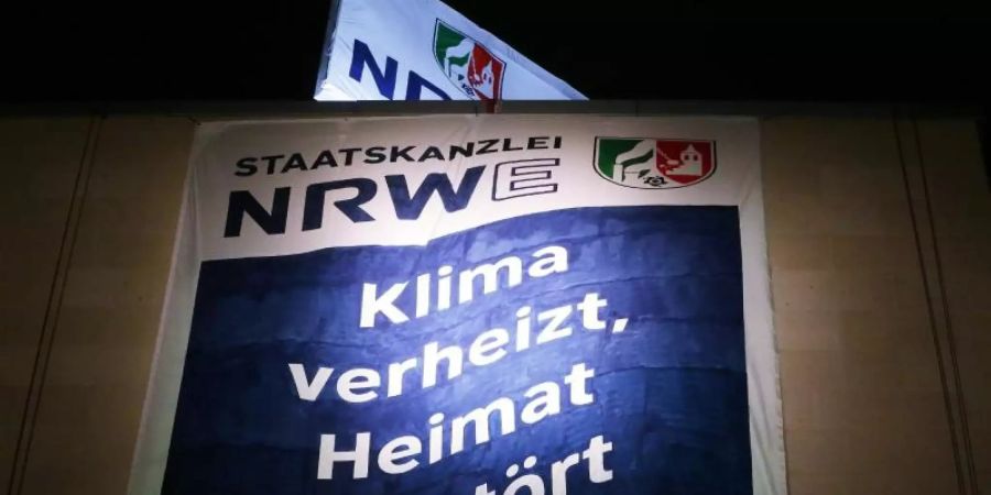 Greenpeace Aktivisten haben am Düsseldorfer Staatskanzlei zwei Banner aufgespannt. Auf dem Banner steht «Staatskanzlei NRWE: Klima verheizt, Heimat zerstört». Foto: David Young/dpa