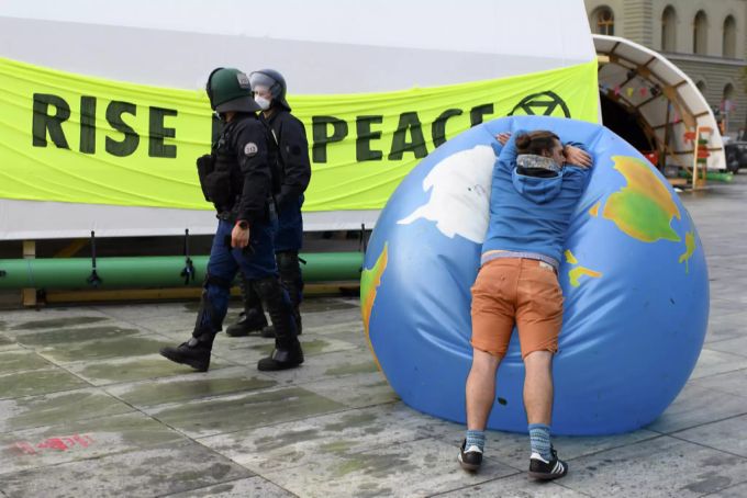 Ein Klima-Aktivist lässt die Luft aus einem Welt-Ball nach der Räumung des Besetzer-Camps auf dem Bundesplatz. Klima-Aktivist Rise Bundesplatz