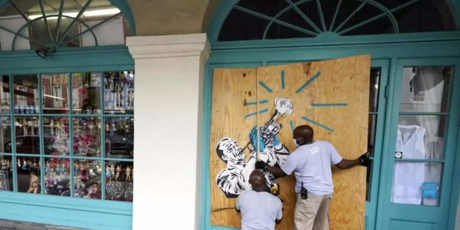 Arbeiter vernageln in Vorbereitung auf Sturm «Marco» die Scheiben eines Geschäfts in New Orleans. Foto: Gerald Herbert/AP/dpa