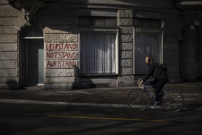 Eine Frau fahrt ein Fahrrad vor einem Gebäude mit der gesprayten Aufschrift «Leerstand, Notstand, Aufstand» (Archivbild). Zürich