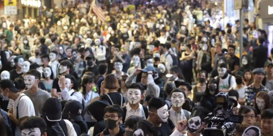 Maskierte Demonstranten versammeln sich auf einer Strasse in Hongkong. Foto: Kin Cheung/AP/dpa