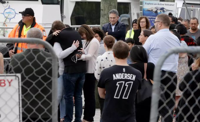Familienmitgliedern der Opfer des Vulkanausbruchs auf der Insel White Island umarmen sich, nachdem sie nach einem Segen auf See wieder an Land sind. Vulkanausbruch auf neuseeländischer Insel