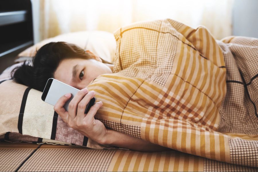 Teenager-Junge im Bett, Smartphone