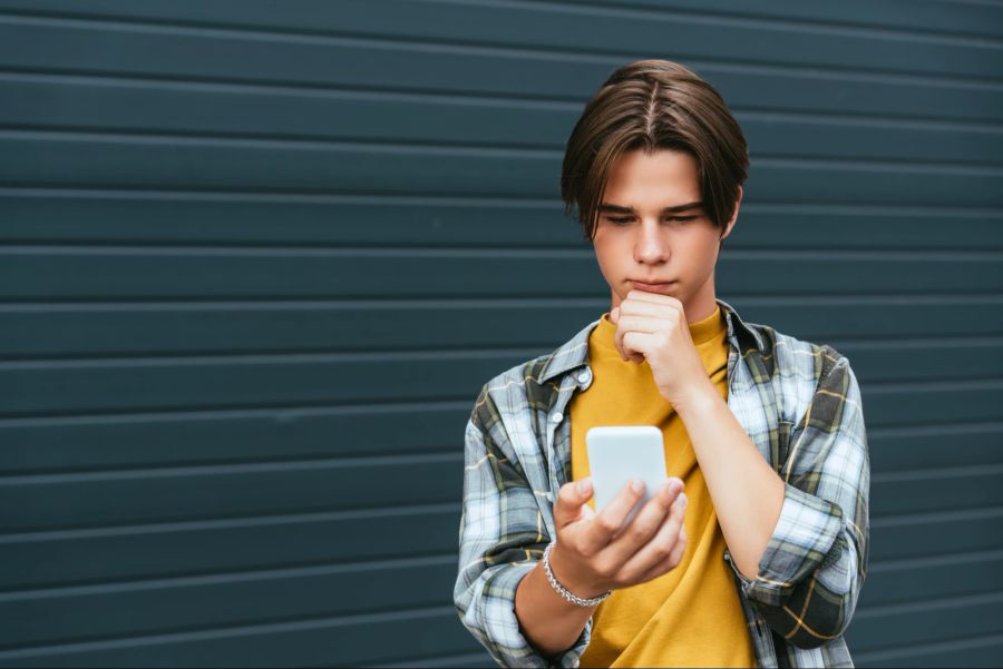 Nachdenklicher Teenager-Junge am Smartphone