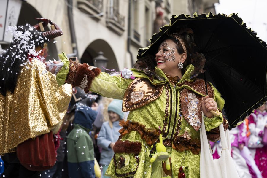 Eine Umzugs-Teilnehmerin wirft Konfetti auf das Publikum.