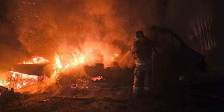 HANDOUT - Auf diesem vom ukrainischen Rettungsdienst via AP zur Verfügung gestellten Foto löscht ein Rettungshelfer das Feuer eines durch einen russischen Angriff zerstörten Autos. F...