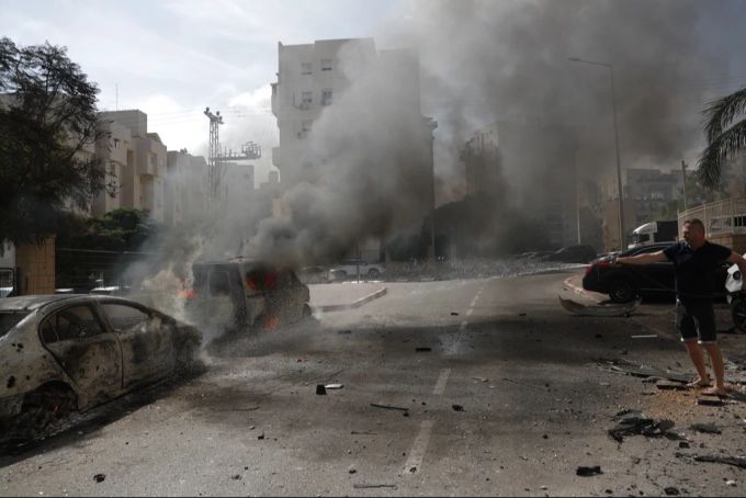 Ein Anwohner löscht brennende Fahrzeuge in der israelischen Stadt Aschkelon nach Raketenabschüssen aus dem Gazastreifen, 07. Oktober 2023. Gazastreifen