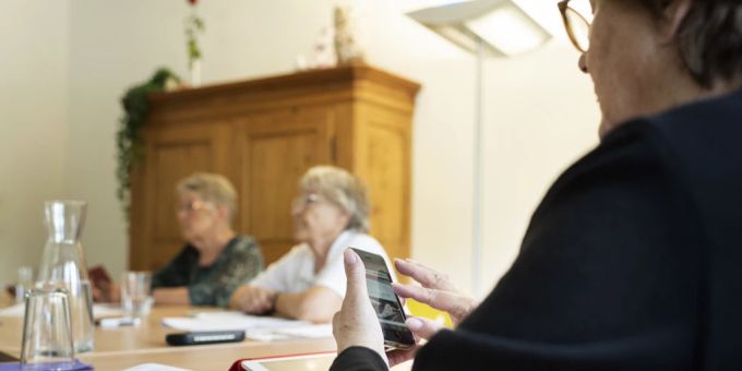 Immer mehr Menschen im gehobenen Alter nutzen ein Handy. Die Gründe sind vielseitig. Seniorin am Tisch bedient Handy