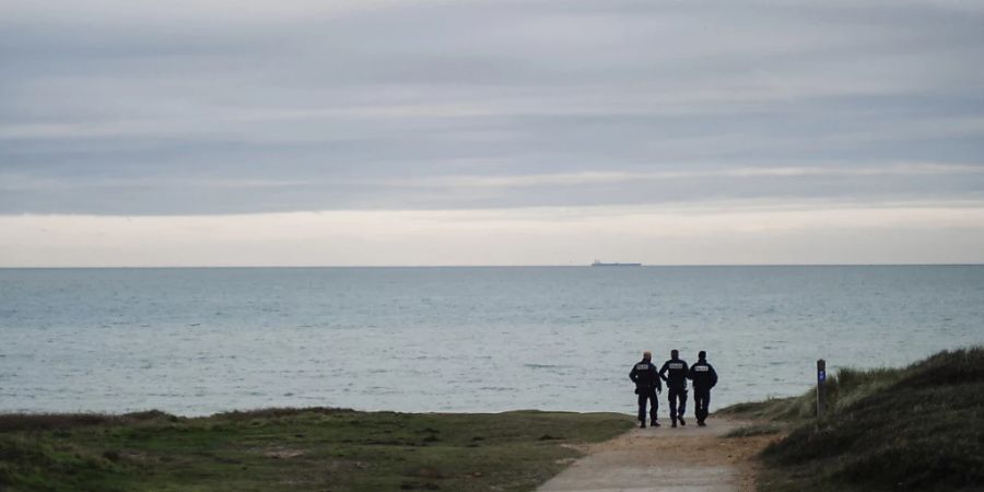 ARCHIV - Französische Polizisten patrouillieren am Strand auf der Suche nach Migranten. Foto: Louis Witter/AP/dpa