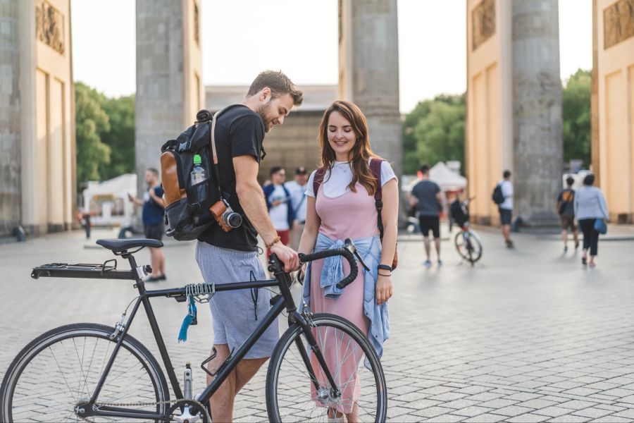 Mann und Frau mit Fahrrad vor dem Brandenburger Tor.