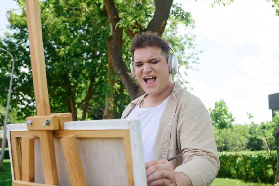 Mann Kopfhörer Staffelei Garten
