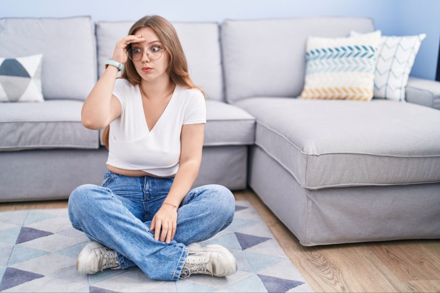 Erstaunte, nachdenkliche junge Frau im Wohnzimmer