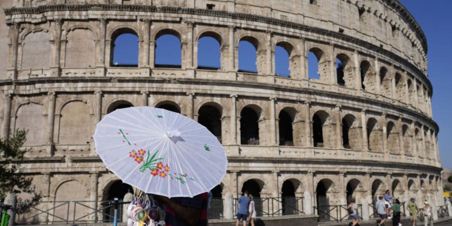 ARCHIV - Ein Mann verkauft Regenschirme vor dem Kolosseum. Foto: Gregorio Borgia/AP/dpa/Archivbild