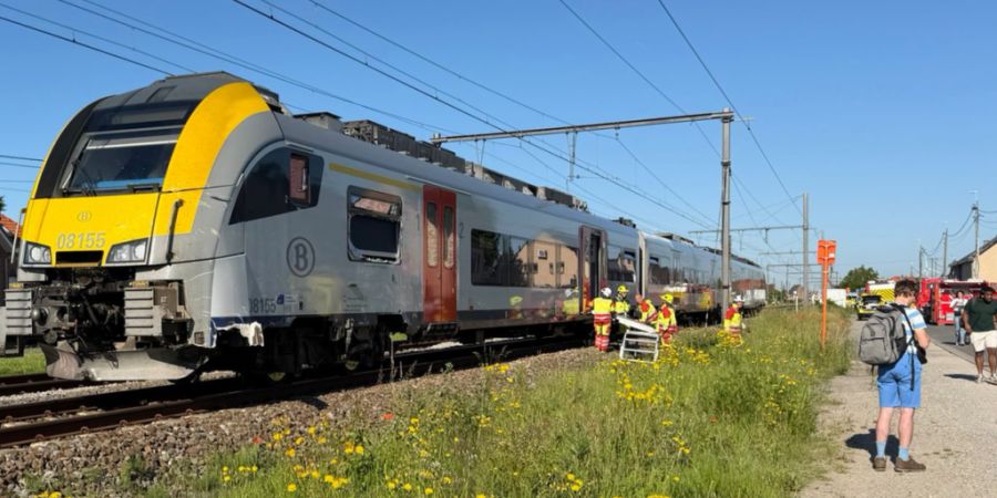 Rettungskräfte sind bei einem Unfallort im Einsatz, nachdem ein Zug mit einem Schulbus am Bahnübergang Vierhuizen in Buggenhout zusammengestoßen war. Foto: Koen Baten/AP/dpa