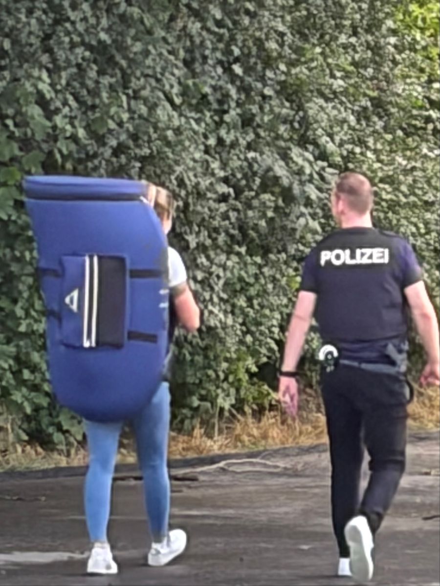 Konzertende: Die Kantonspolizistin trägt das 13 Kilo schwere Instrument weg - ihr Kollege bietet Geleitschutz.