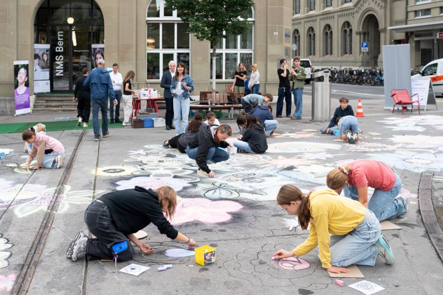 Kreidekunst vor der NMS Bern – Schülerinnen und Schüler gestalten gemeinsam ein buntes Blumenmeer auf dem Waisenhausplatz.