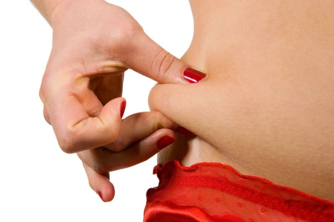 Frau greift Hüftspeck mit der Hand