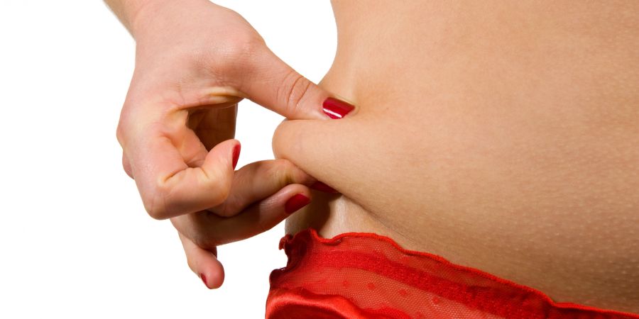 Frau greift Hüftspeck mit der Hand